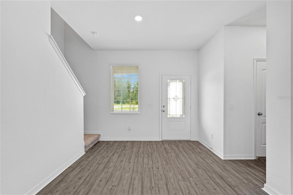 An entryway with wood-look flooring, a white front door, a window, and a staircase — 560 BAY LEAF DRIVE, POINCIANA, FL