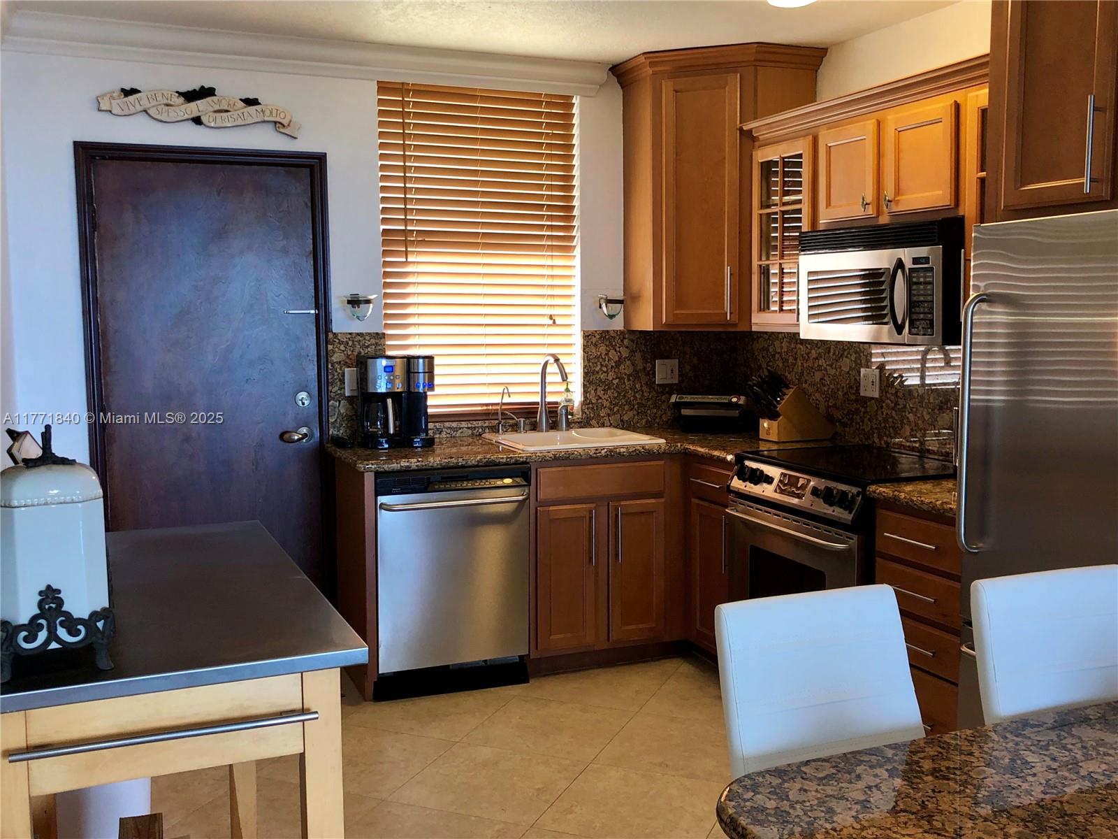 A kitchen features wood cabinets, granite countertops, stainless steel appliances, and a window with blinds — 1936 S Ocean Dr # 24C, Hallandale Beach FL 33009, HALLANDALE BEACH, FL