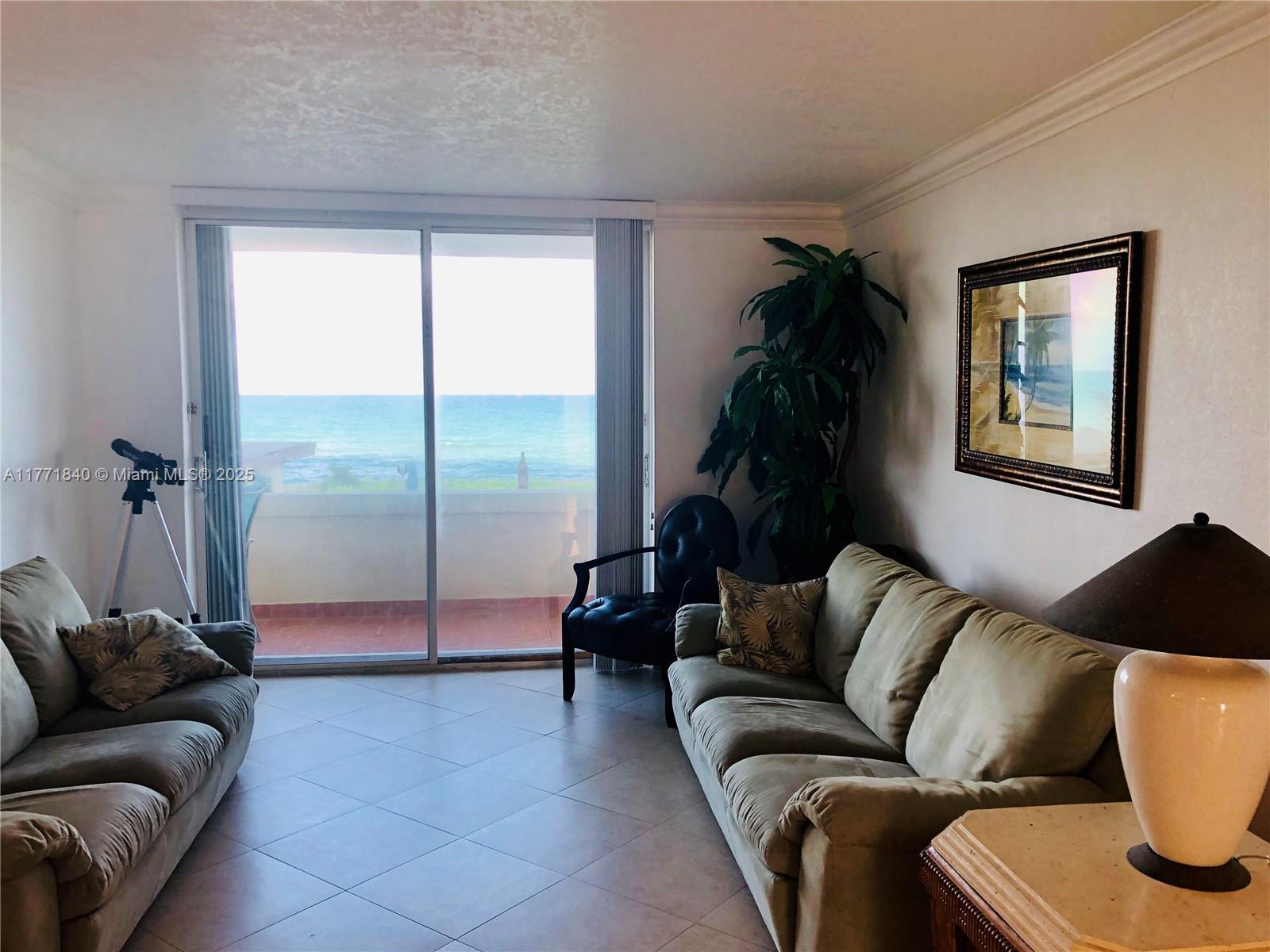 A living room with two sofas, a telescope, and a sliding door overlooking the ocean — 1936 S Ocean Dr # 24C, Hallandale Beach FL 33009, HALLANDALE BEACH, FL