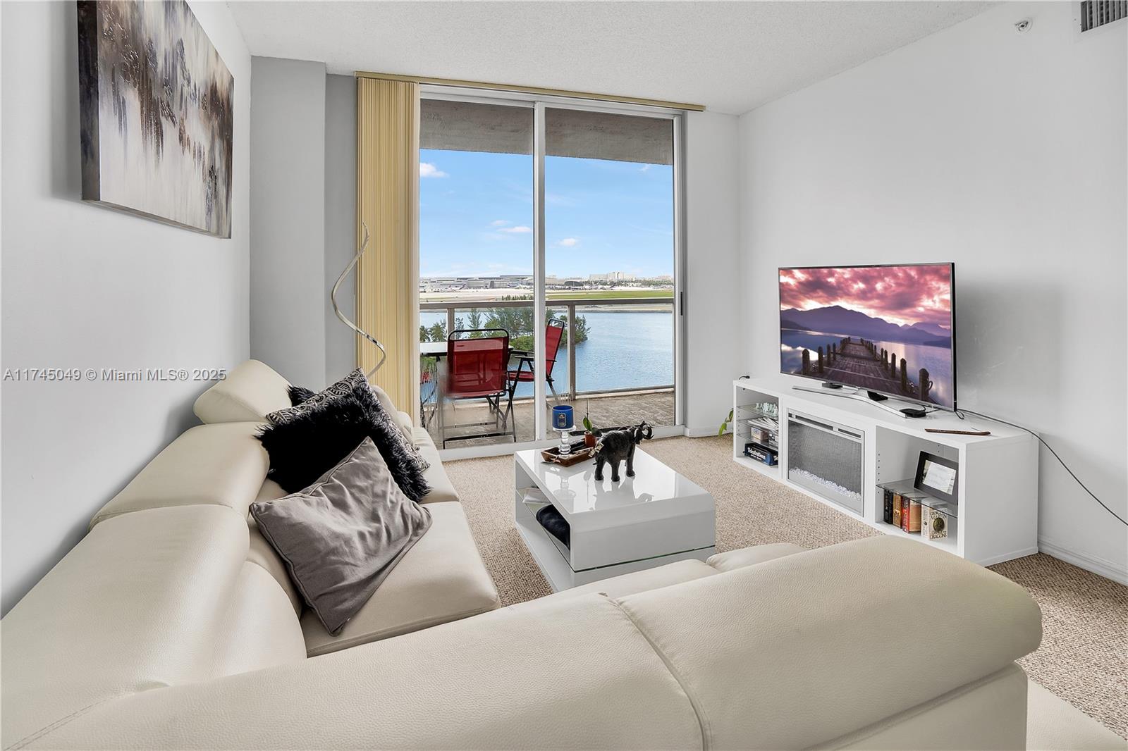 A living room features a white sectional sofa, a coffee table, and a balcony view — 5091 NW 7th St # 1001, Miami FL 33126, MIAMI, FL