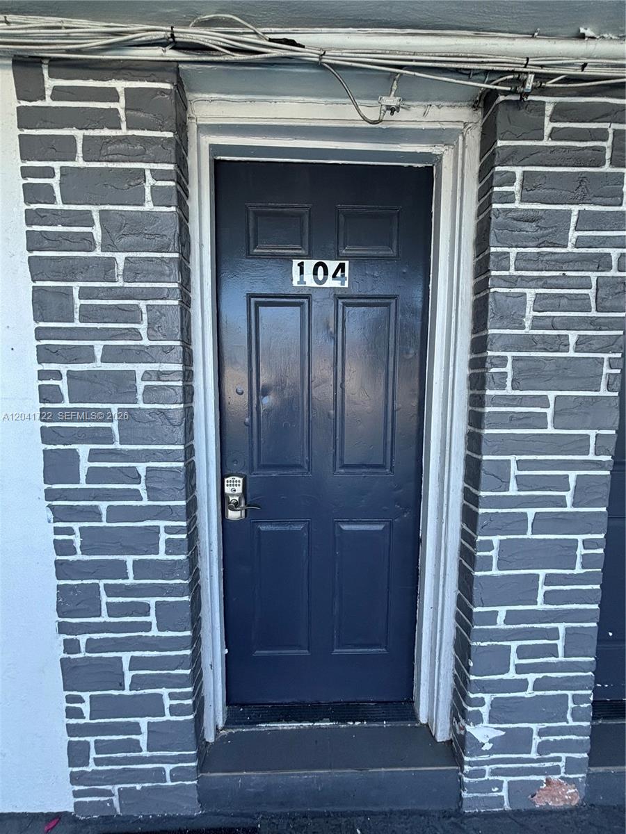 A dark blue door labeled 104 is framed by gray stone veneer pillars — 1843 Dewey St # 104, Hollywood FL 33020, HOLLYWOOD, FL