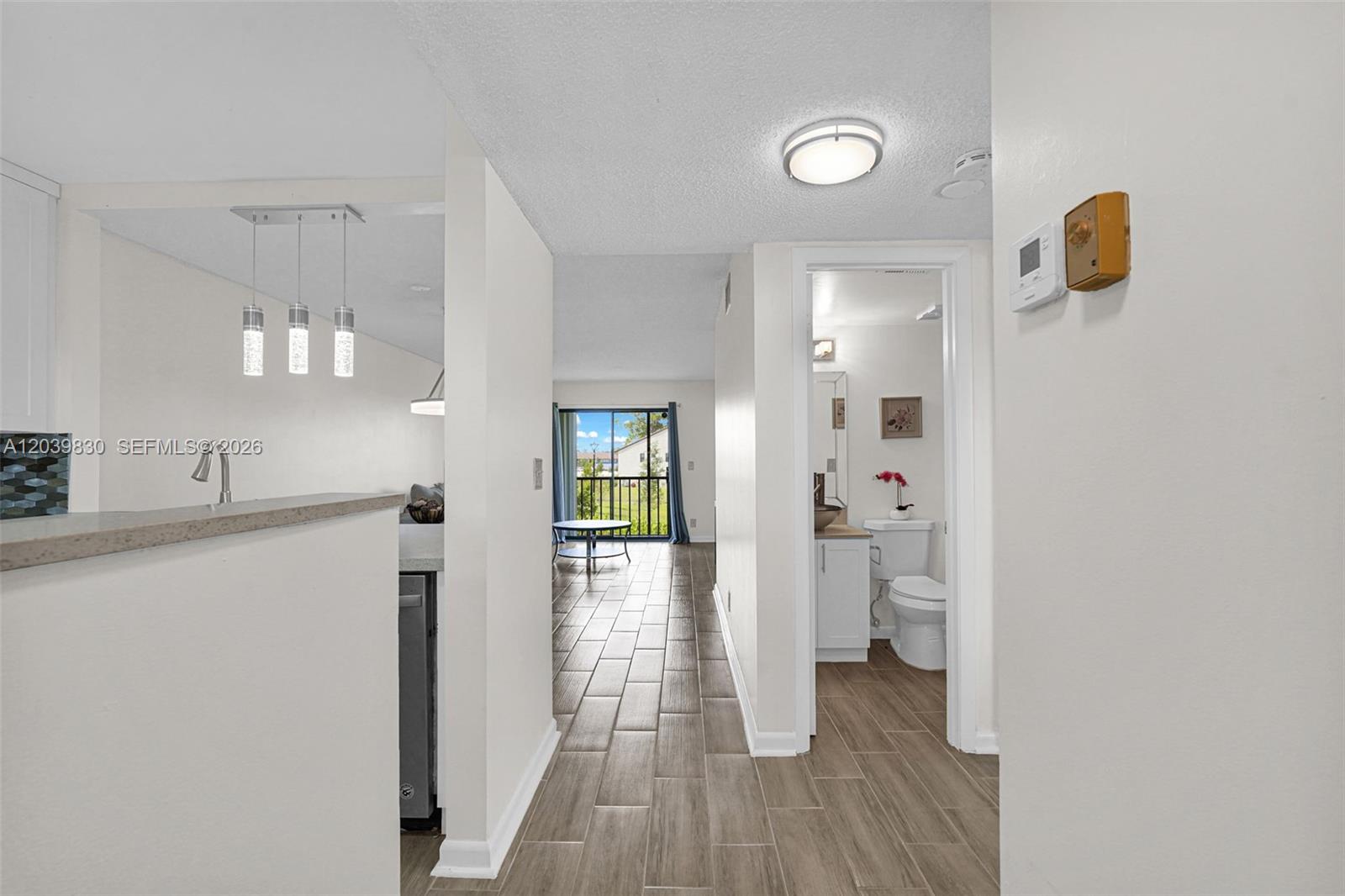 A hallway with tile flooring leads toward a living area with a balcony view — 7142 Golf Colony Ct # 206, Lake Worth FL 33467, LAKE WORTH, FL