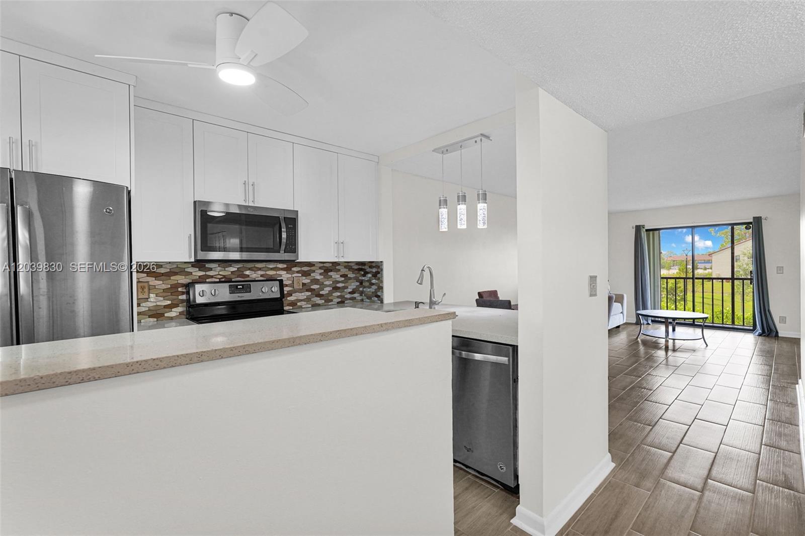 A kitchen with white cabinets and a mosaic backsplash opens to a living area — 7142 Golf Colony Ct # 206, Lake Worth FL 33467, LAKE WORTH, FL