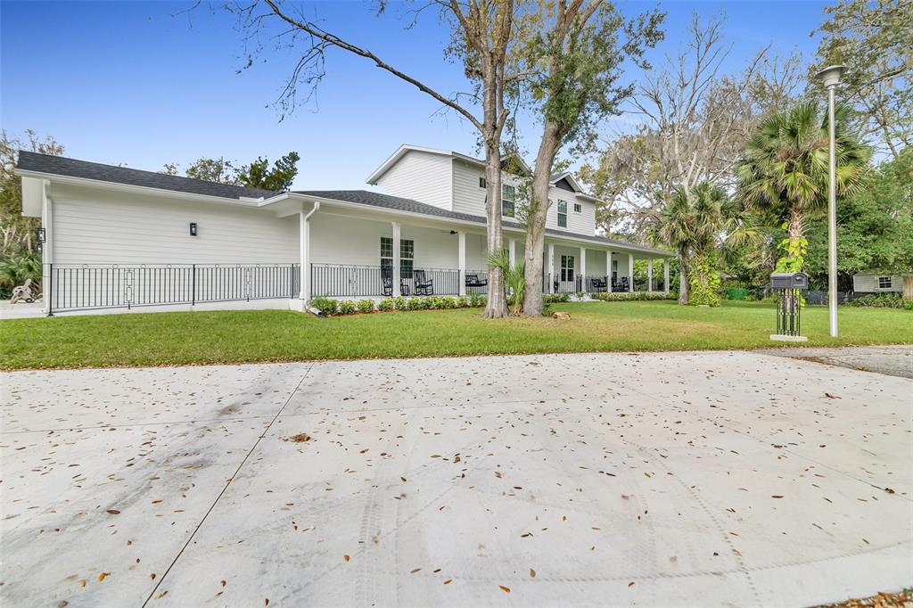 A white two-story house with a long front porch and black metal railing — 599 GLENDEVON DRIVE, NEW SMYRNA BEACH, FL