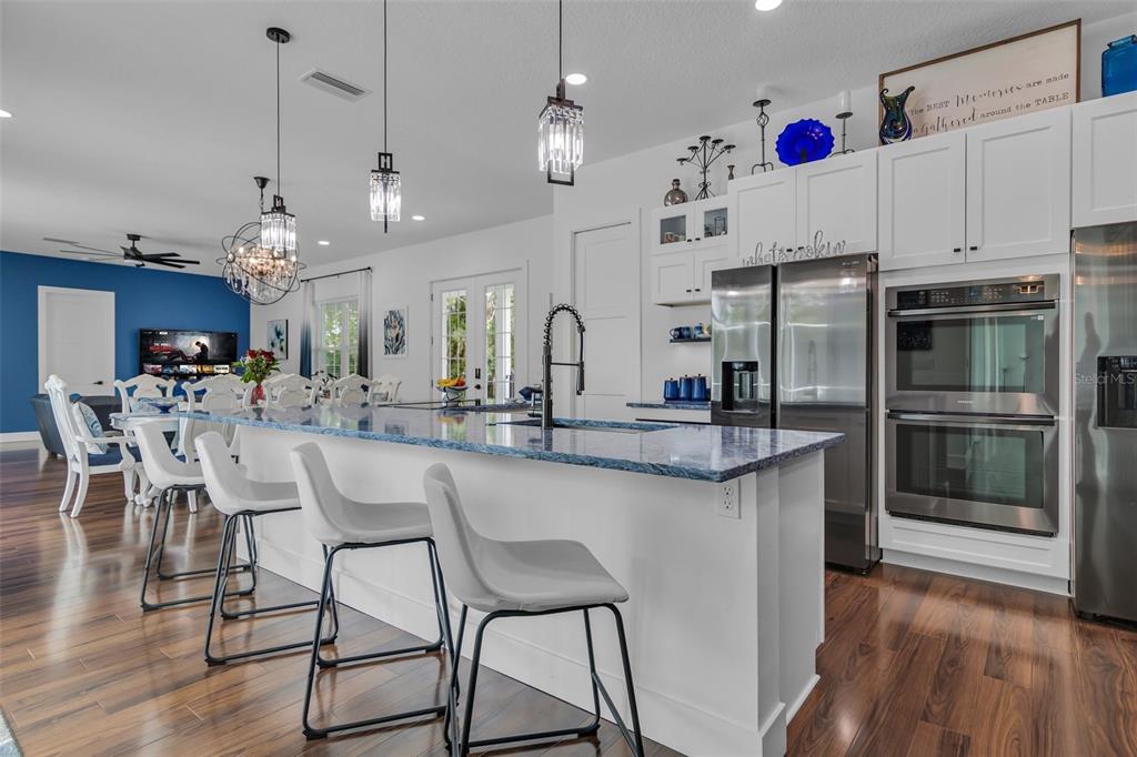 A modern kitchen features a blue-patterned island, white cabinetry, stainless steel appliances, and pendant lighting — 599 GLENDEVON DRIVE, NEW SMYRNA BEACH, FL