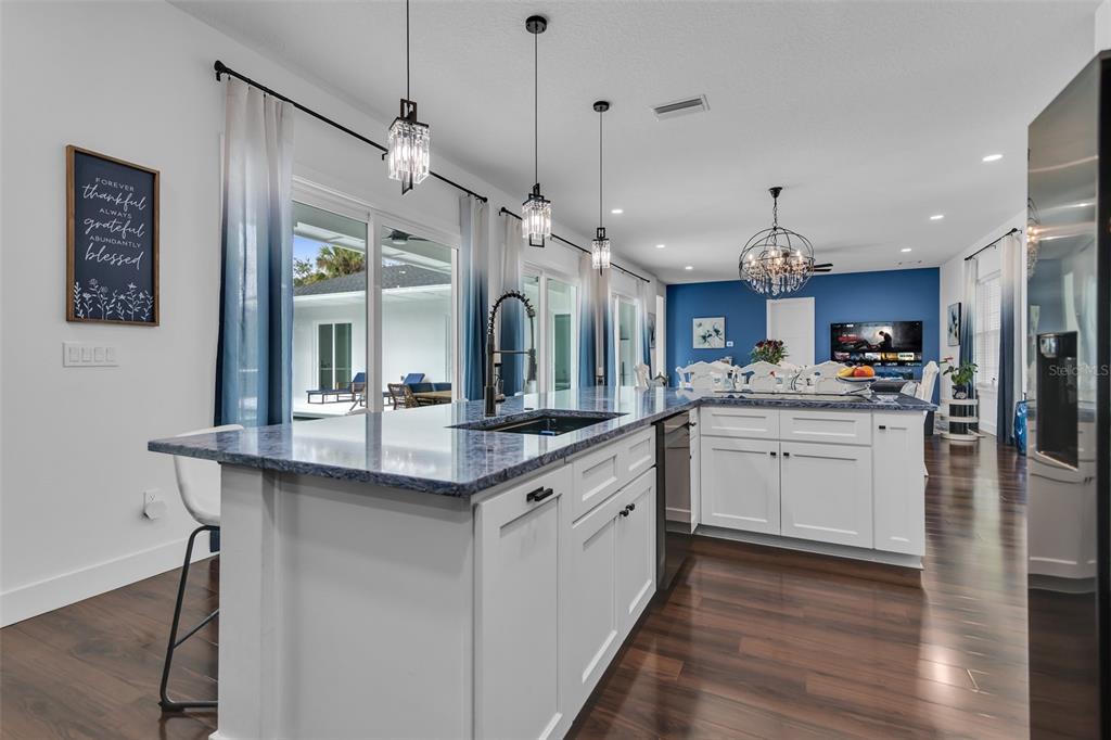 A modern kitchen features a large island with blue countertops, white cabinetry, and pendant lighting — 599 GLENDEVON DRIVE, NEW SMYRNA BEACH, FL