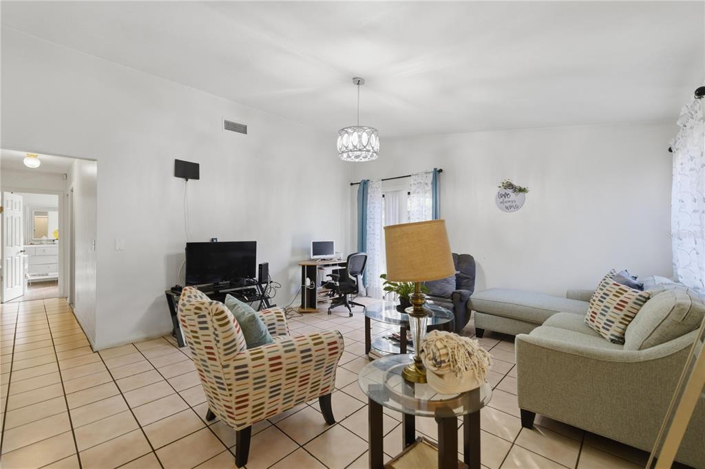 A living room features tiled floors, a patterned armchair, a sectional sofa, and a desk area — 1939 SW 73RD TERRACE, GAINESVILLE, FL