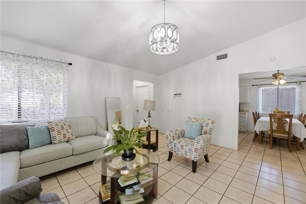 A living room features light-colored tile flooring, a patterned armchair, and a glass coffee table — 1939 SW 73RD TERRACE, GAINESVILLE, FL