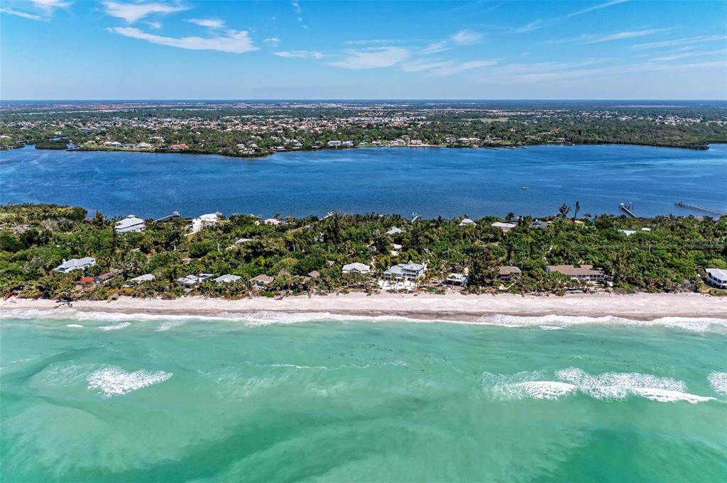 An aerial view shows a sandy beach, waterfront homes, and a large bay under blue skies — 7520 MANASOTA KEY ROAD, ENGLEWOOD, FL