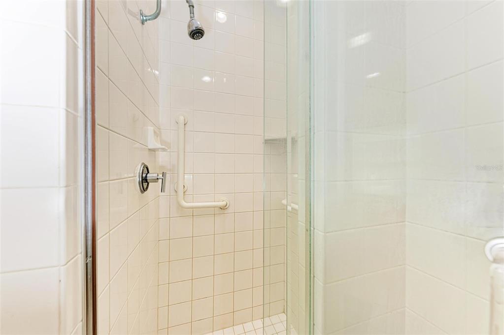 A tiled shower stall features a glass door, a wall-mounted grab bar, and a showerhead — 7520 MANASOTA KEY ROAD, ENGLEWOOD, FL