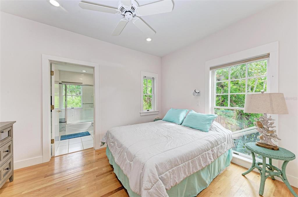 A bedroom features a queen bed, hardwood floors, a ceiling fan, and an attached bathroom — 7520 MANASOTA KEY ROAD, ENGLEWOOD, FL
