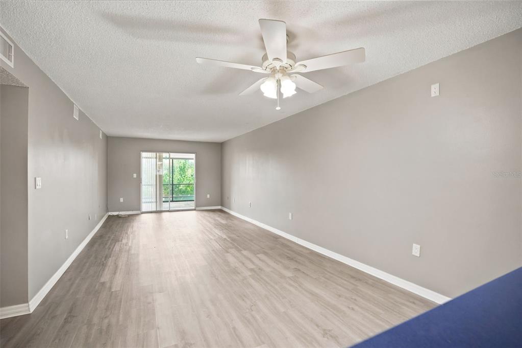 An empty living room features light gray walls, wood-look flooring, and a ceiling fan — 90 S HIGHLAND AVENUE UNIT 1414, TARPON SPRINGS, FL