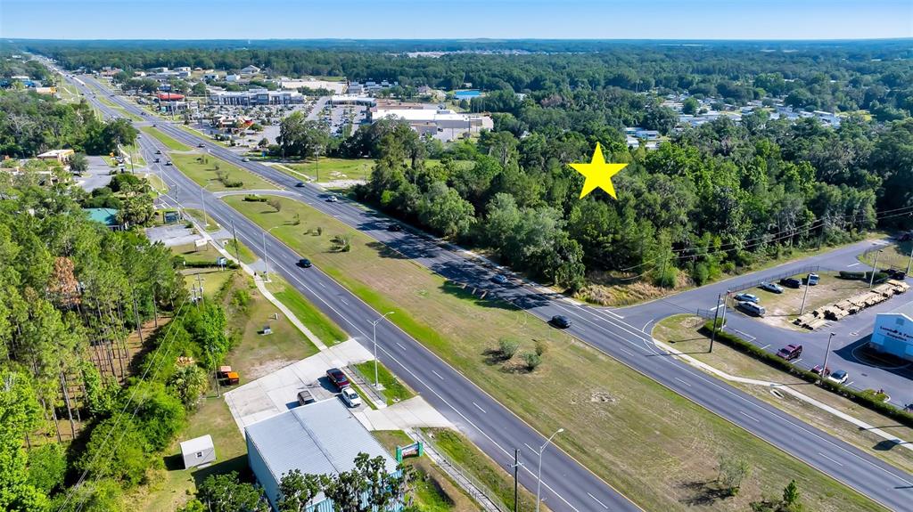 An aerial view shows a wooded lot marked with a yellow star beside a highway — 4799 SE 106TH PLACE ROAD, BELLEVIEW, FL