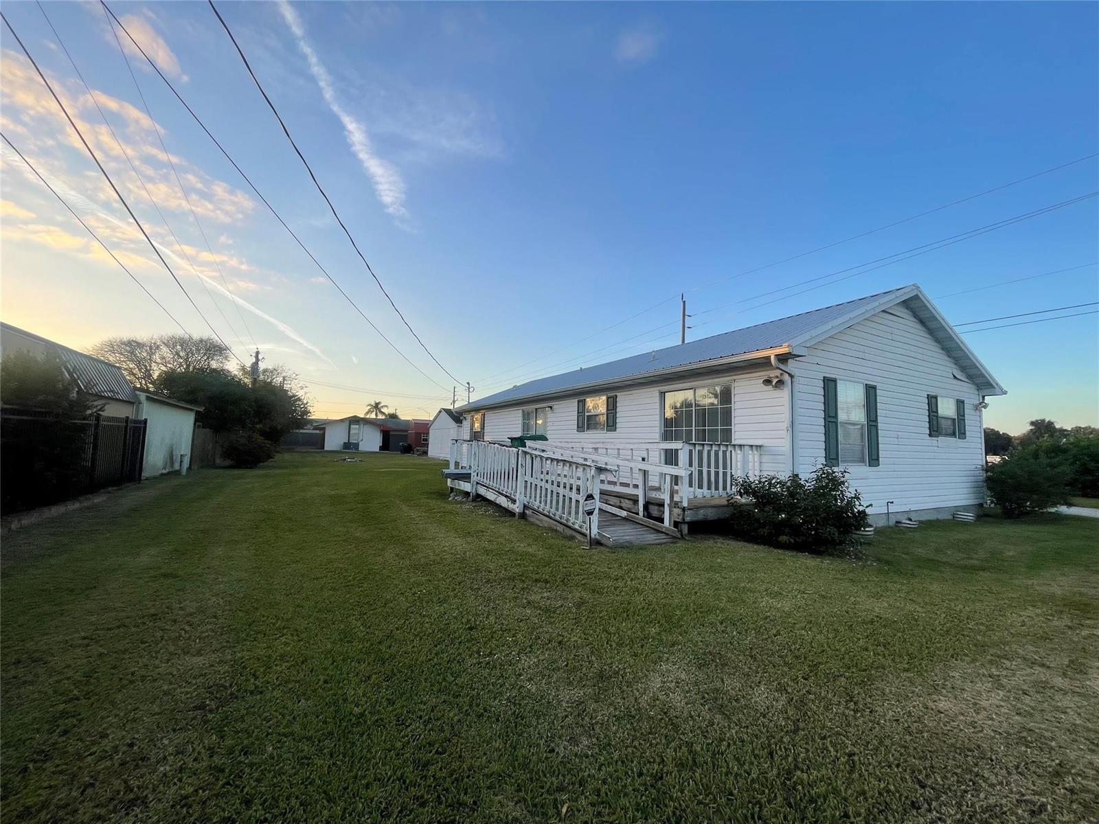 A white single-story house features a wooden wheelchair ramp leading to the back entrance — 2130 State Road 70, Okeechobee FL 34972, OKEECHOBEE, FL