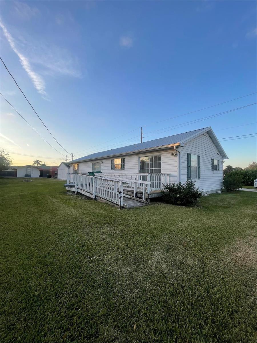 A white, single-story house with a metal roof and a wooden wheelchair ramp — 2130 State Road 70, Okeechobee FL 34972, OKEECHOBEE, FL