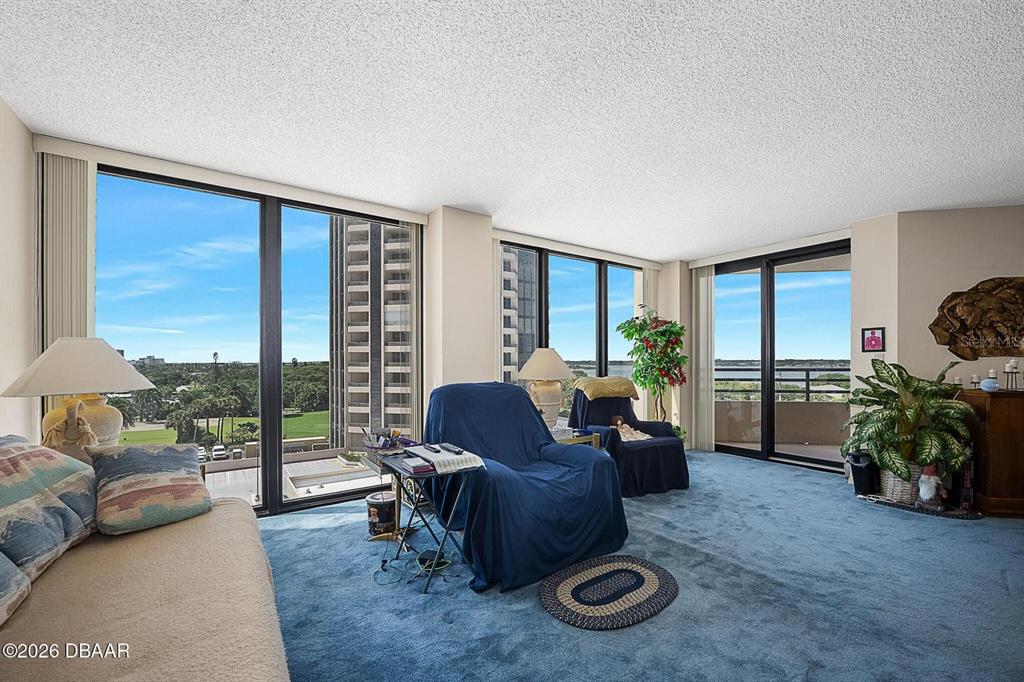 A living room with blue carpeting, floor-to-ceiling windows, and a view of the outdoors — 1 OCEANS WEST BOULEVARD UNIT 5A5, DAYTONA BEACH, FL