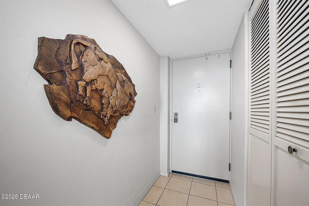 An entryway features a tiled floor, a white door, and a large bison wall sculpture — 1 OCEANS WEST BOULEVARD UNIT 5A5, DAYTONA BEACH, FL