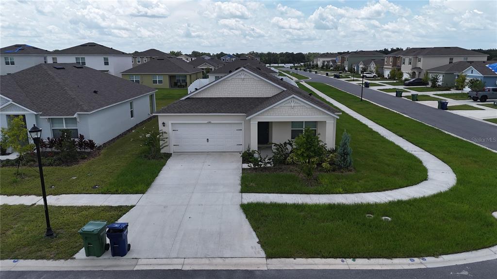 An aerial view shows a single-story suburban house with a white garage and driveway — 1340 DAISY FIELD DR, WINTER HAVEN, FL