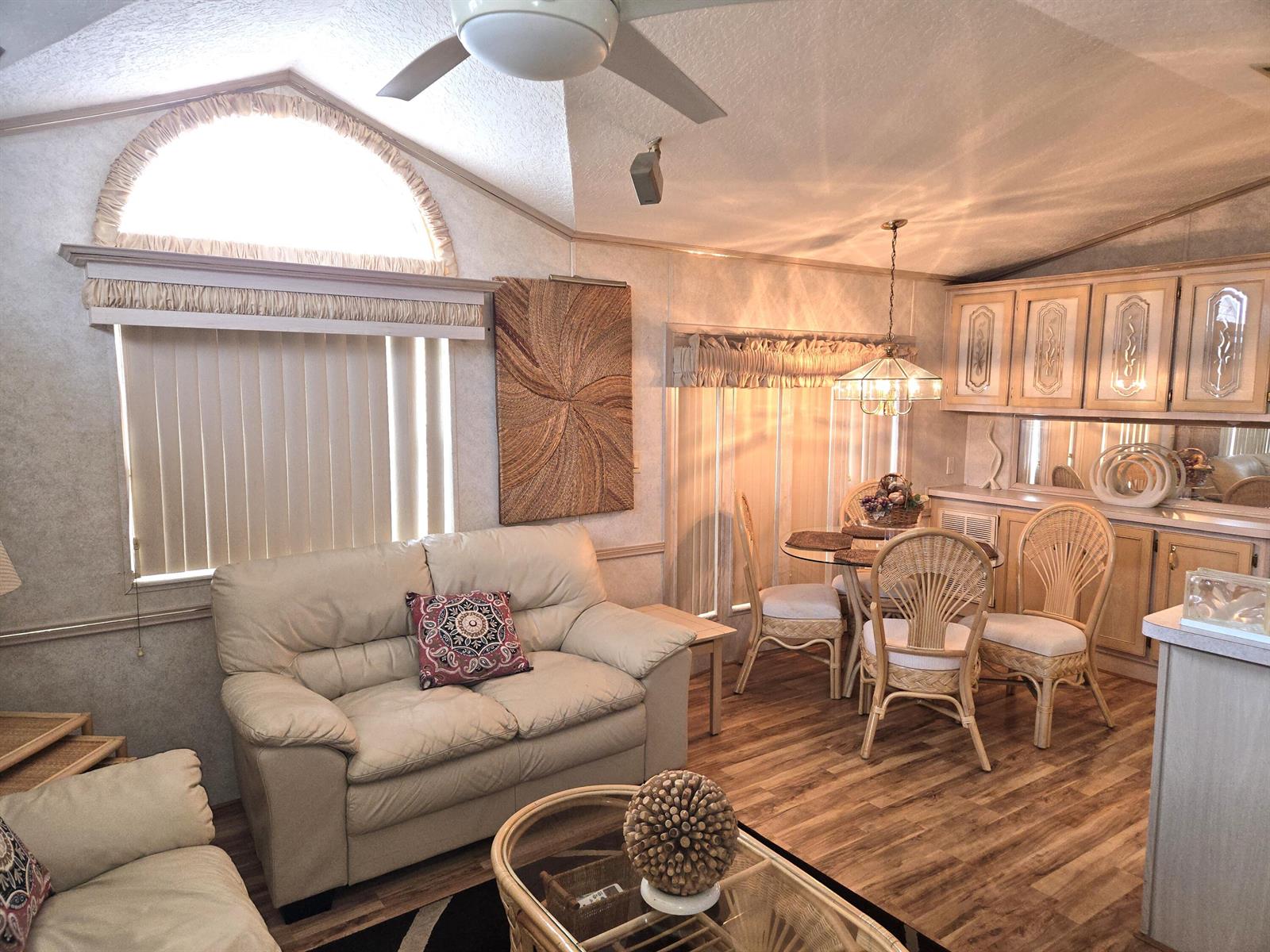 A living and dining area with light-colored furniture, wood-look flooring, and vaulted ceilings — 7950 Hwy 78 W # 314, Okeechobee FL 34974, OKEECHOBEE, FL