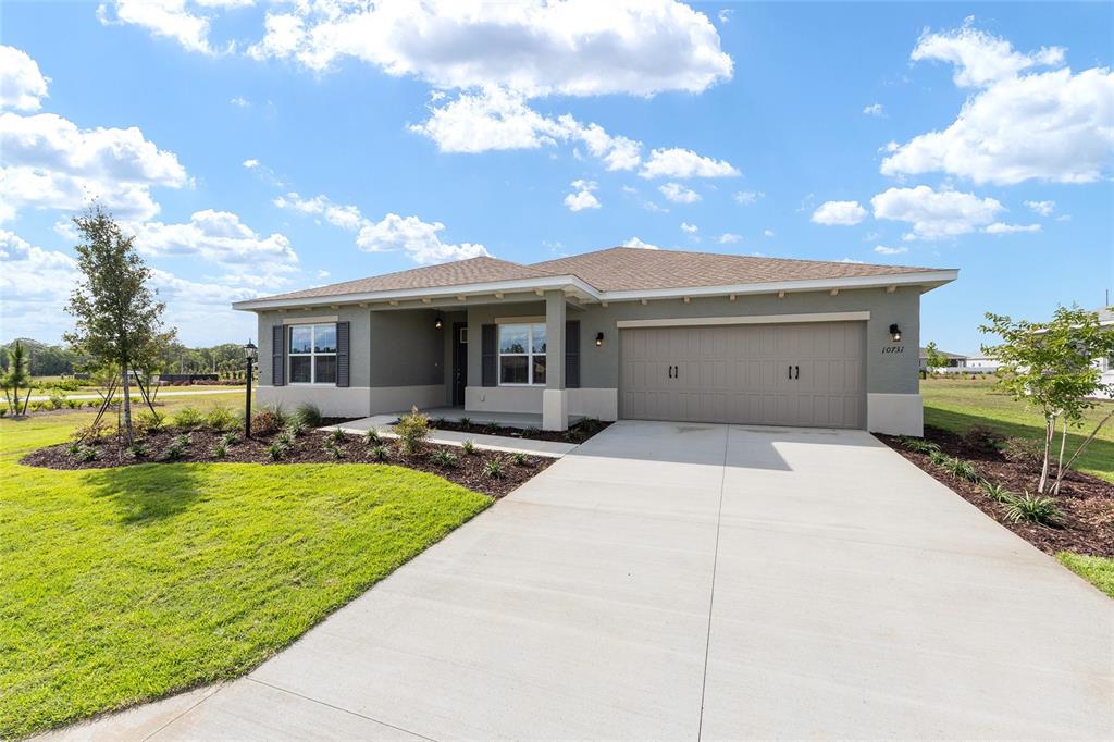A single-story house with a beige exterior, a two-car garage, and a front lawn — 10731 SW 102ND LANE, OCALA, FL