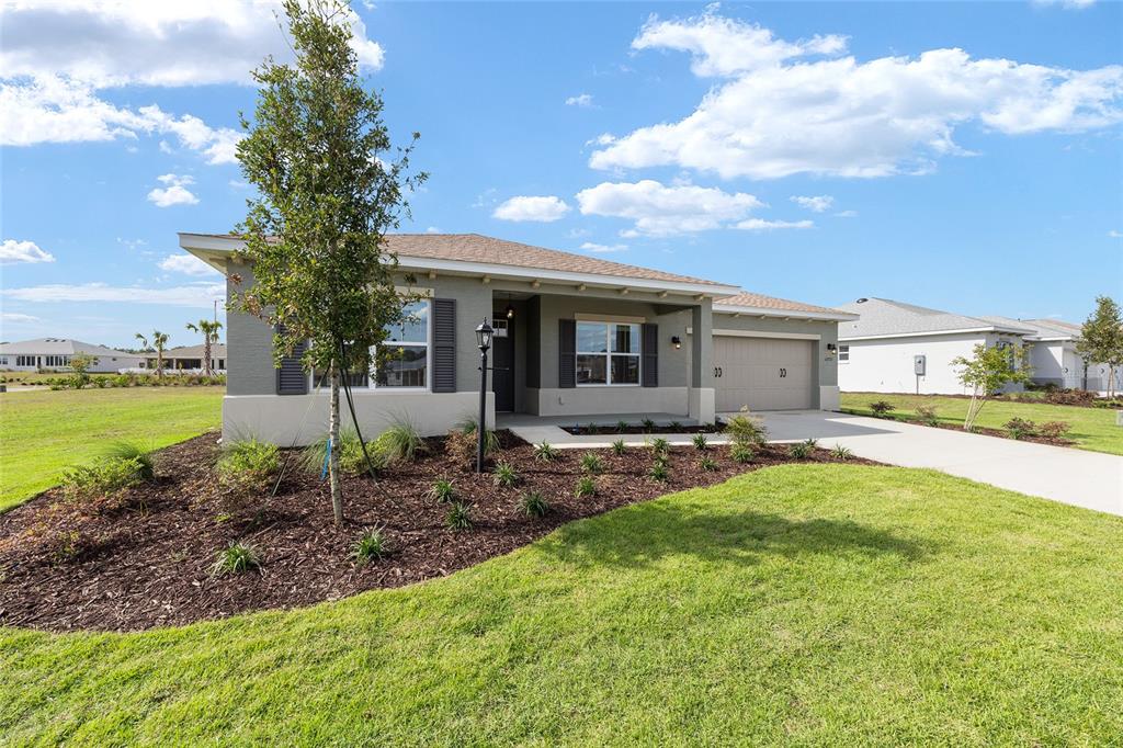 A single-story house with a gray exterior, a two-car garage, and a landscaped front yard — 10731 SW 102ND LANE, OCALA, FL