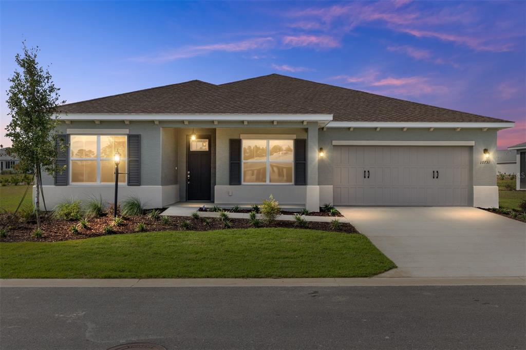 A single-story house with a gray stucco exterior, dark shutters, and a two-car garage — 10731 SW 102ND LANE, OCALA, FL