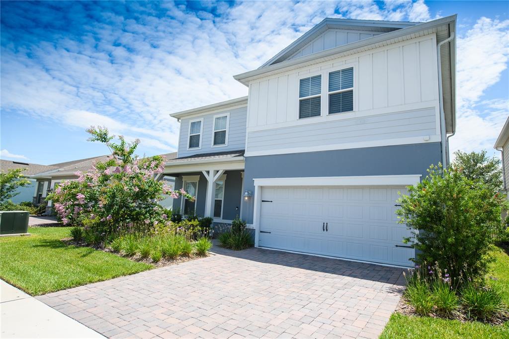 A two-story house with blue and white siding features a paved driveway and garage — 10746 PAHOKEE BEACH PLACE, ORLANDO, FL