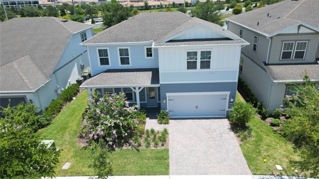 An aerial view of a two-story blue house with a paver driveway and front porch — 10746 PAHOKEE BEACH PLACE, ORLANDO, FL