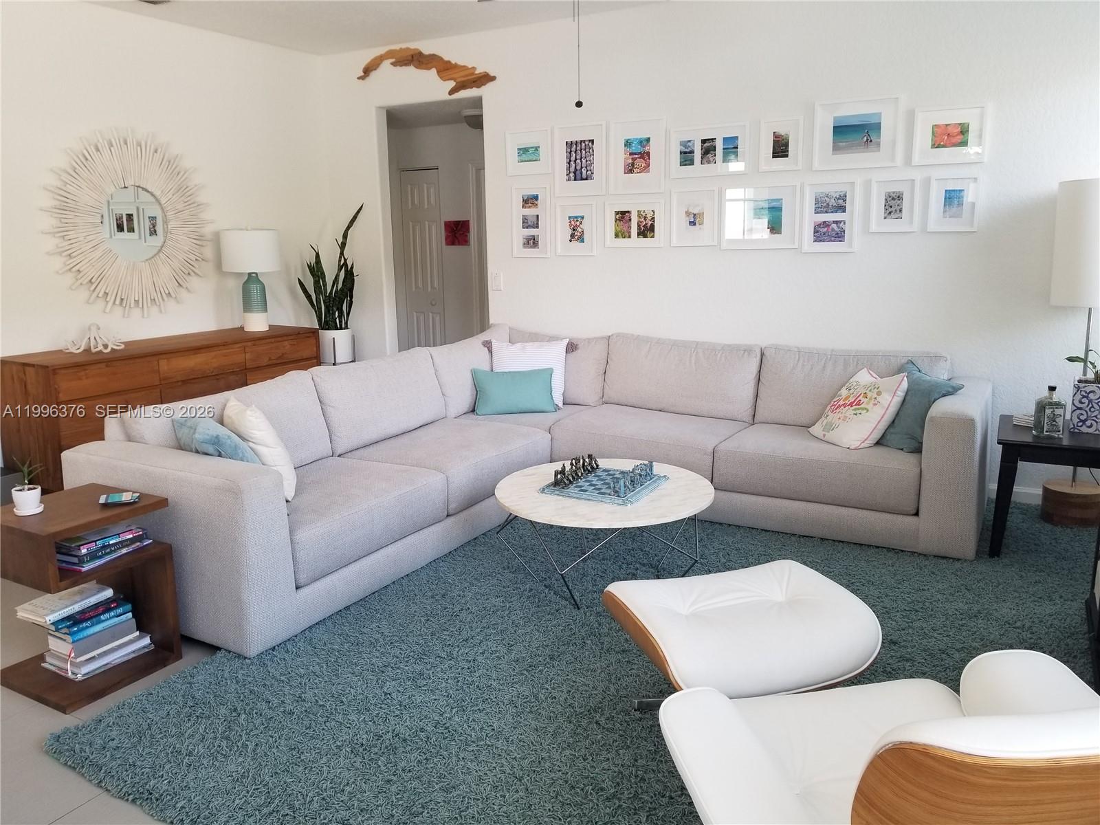 A living room features a large gray sectional sofa, a round coffee table, and gallery wall — 4719 NW 96th Pl, Doral FL 33178, DORAL, FL