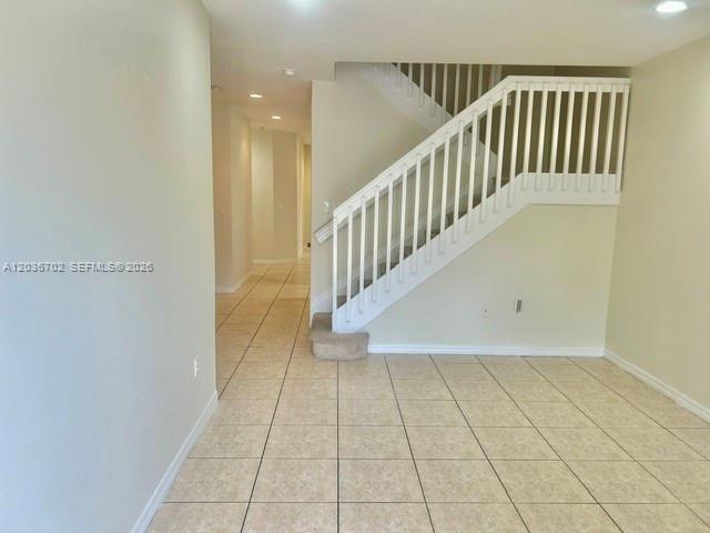 An interior view shows a room with tiled floors and a white staircase with railings — 568 NE 35th Ave, Homestead FL 33033, HOMESTEAD, FL