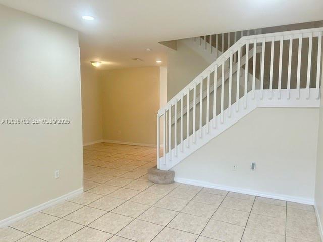 An interior view shows a tiled room with a staircase featuring a white railing — 568 NE 35th Ave, Homestead FL 33033, HOMESTEAD, FL