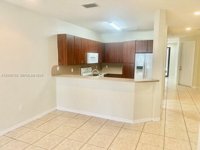A kitchen features dark wood cabinets, stainless steel appliances, and a tiled breakfast bar — 568 NE 35th Ave, Homestead FL 33033, HOMESTEAD, FL