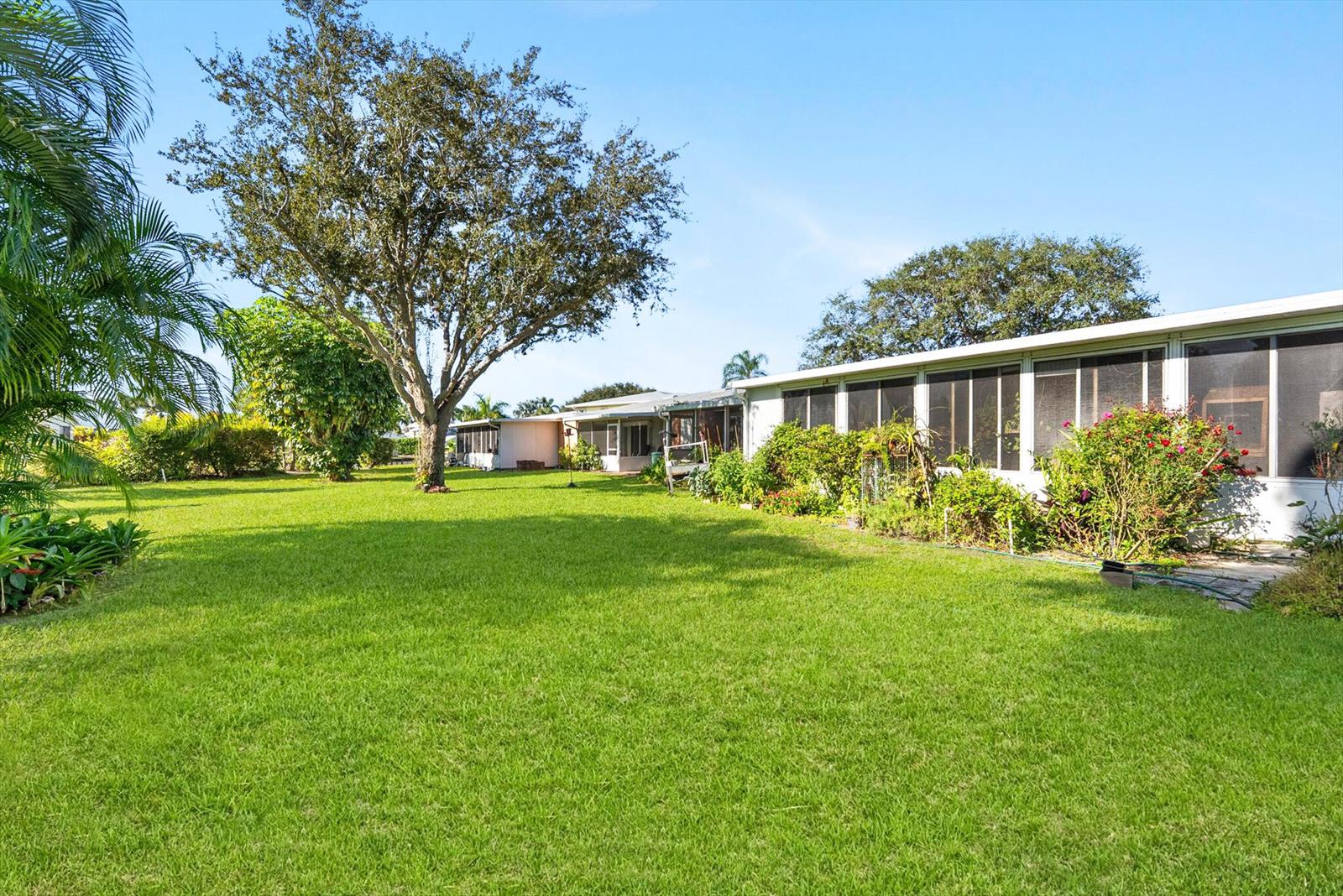 A large green lawn stretches toward a house with a screened-in porch and trees — 1940 NW 13th Street # a, Delray Beach FL 33445, DELRAY BEACH, FL