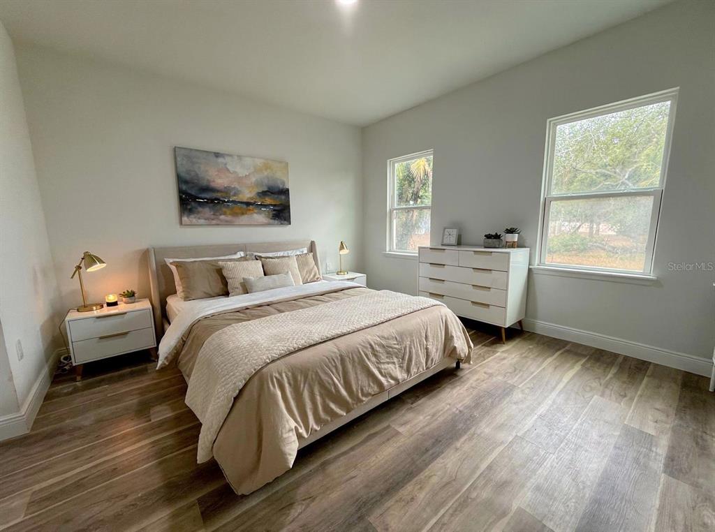 A bedroom features a bed with neutral bedding, a white dresser, and wood-look flooring — 351 TENK STREET, PORT CHARLOTTE, FL
