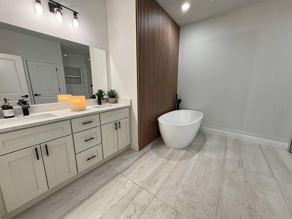 A modern bathroom features a white freestanding tub, a wood-slat accent wall, and a double vanity — 351 TENK STREET, PORT CHARLOTTE, FL