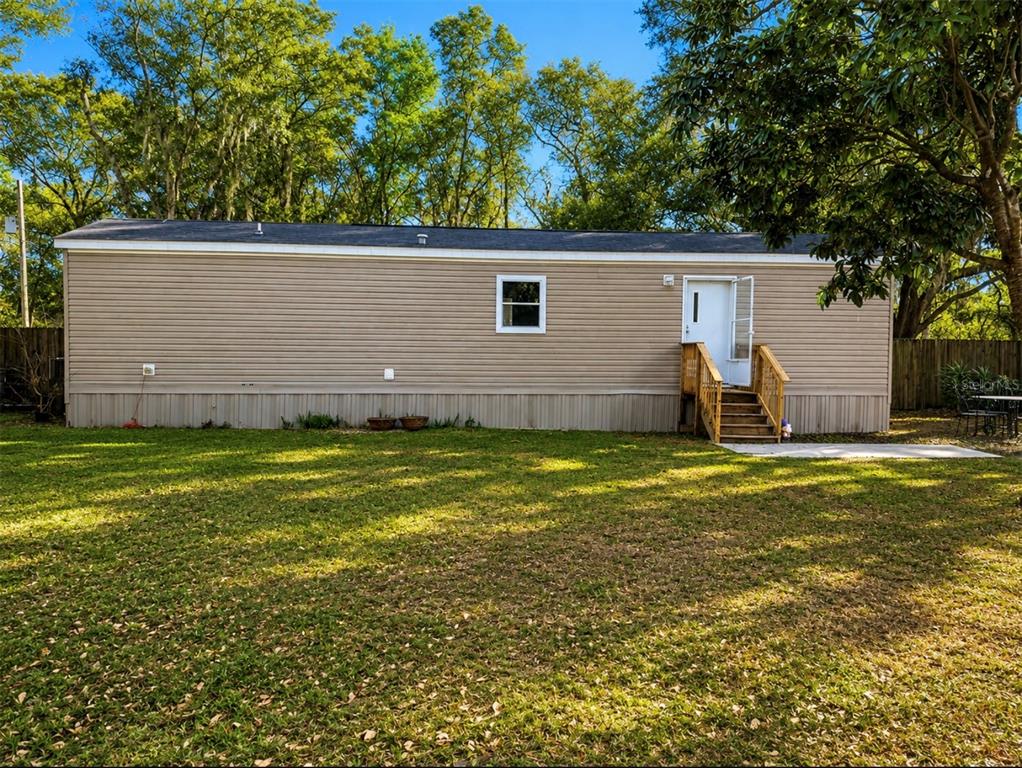 A tan mobile home with a single window and a wooden staircase leading to the door — 25408 ONEAL ROAD, BROOKSVILLE, FL
