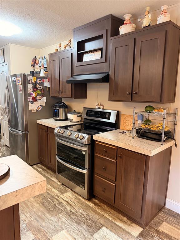 A kitchen features dark wood cabinets, stainless steel appliances, and light-colored laminate countertops — 25408 ONEAL ROAD, BROOKSVILLE, FL