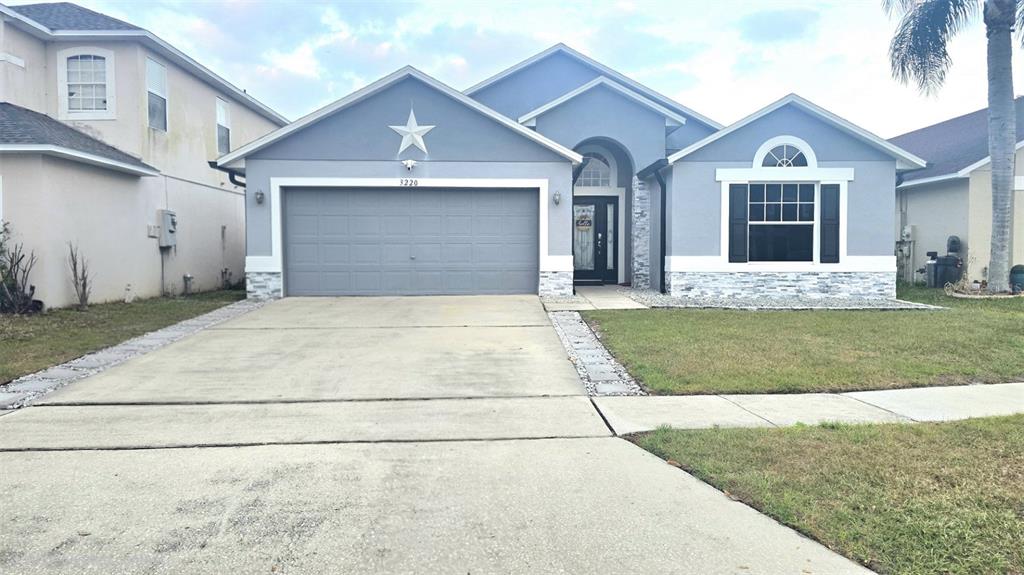 A single-story house with a gray garage, a white star, and stone veneer accents — 3220 ABIAKA DRIVE, KISSIMMEE, FL