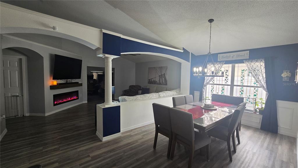 A dining area with a table and chairs opens into a living room with a fireplace — 3220 ABIAKA DRIVE, KISSIMMEE, FL