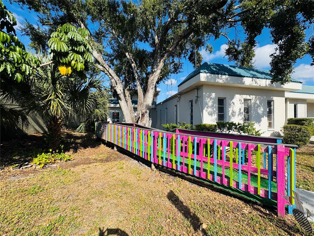 A colorful wooden ramp leads to the entrance of a white building under large trees — 4509 BEE RIDGE ROAD UNIT E, SARASOTA, FL