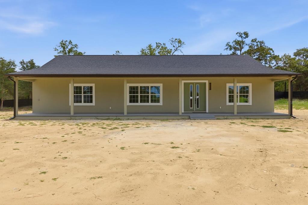 A single-story house with a covered front porch, tan siding, and a dark shingled roof — 5970 W INLAND, DUNNELLON, FL