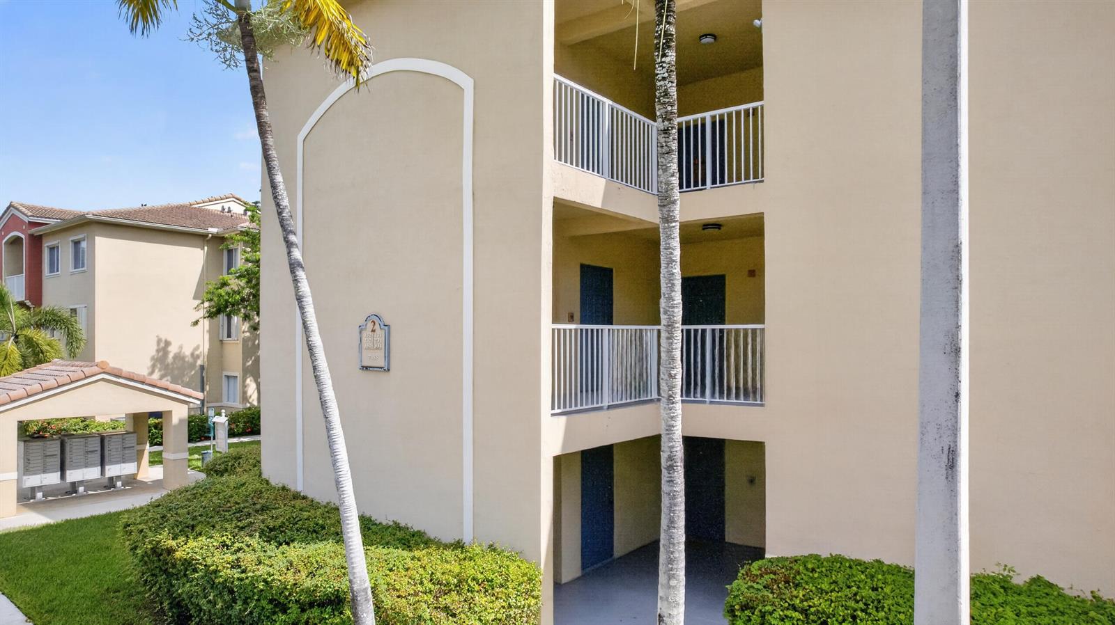A three-story beige apartment building exterior features white railings, palm trees, and a mailbox kiosk — 7085 Nova Drive # 232, Davie FL 33317, DAVIE, FL