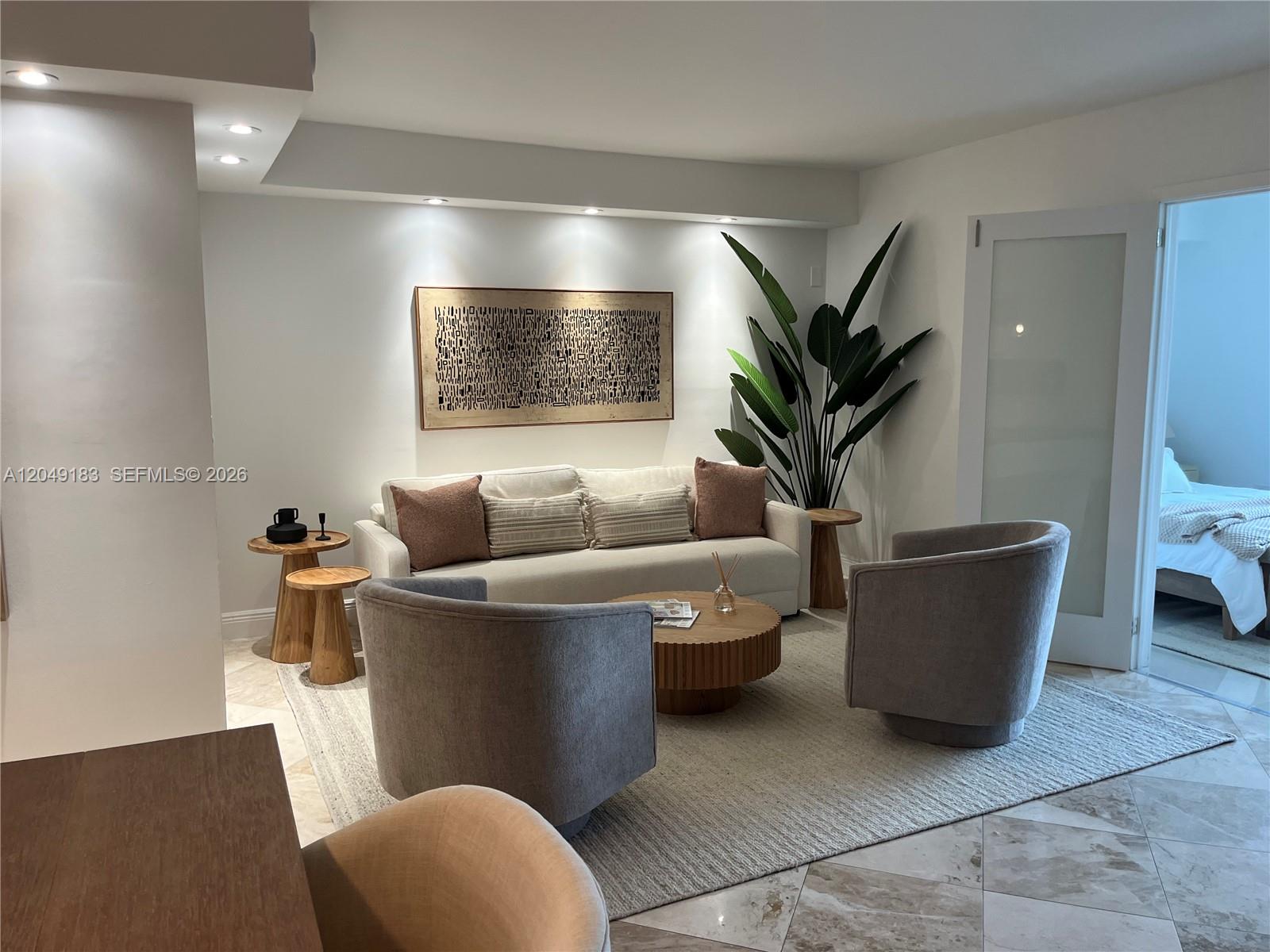 A living room features a sofa, two armchairs, a coffee table, and a large plant — 2301 Collins Ave # 731, Miami Beach FL 33139, MIAMI BEACH, FL