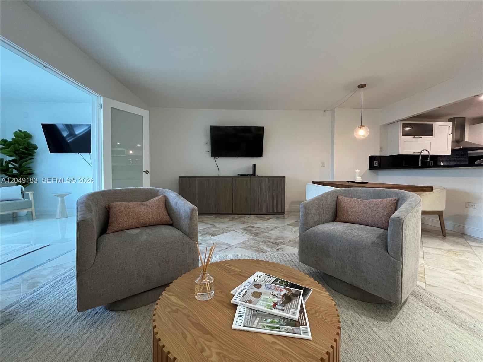 A living room features two grey swivel chairs, a round wooden coffee table, and tile flooring — 2301 Collins Ave # 731, Miami Beach FL 33139, MIAMI BEACH, FL