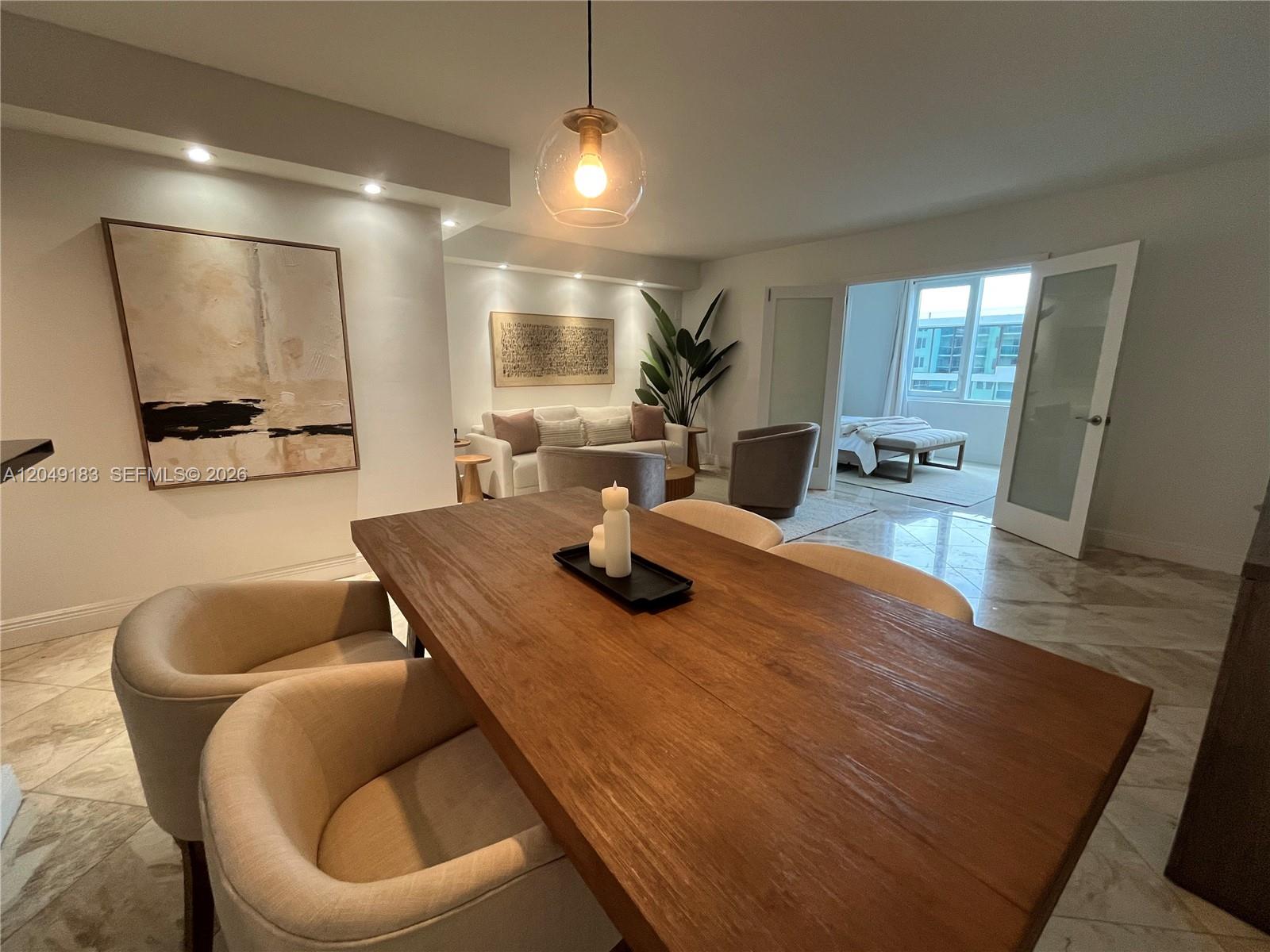 A dining area with a wooden table leads into a living room and bedroom — 2301 Collins Ave # 731, Miami Beach FL 33139, MIAMI BEACH, FL