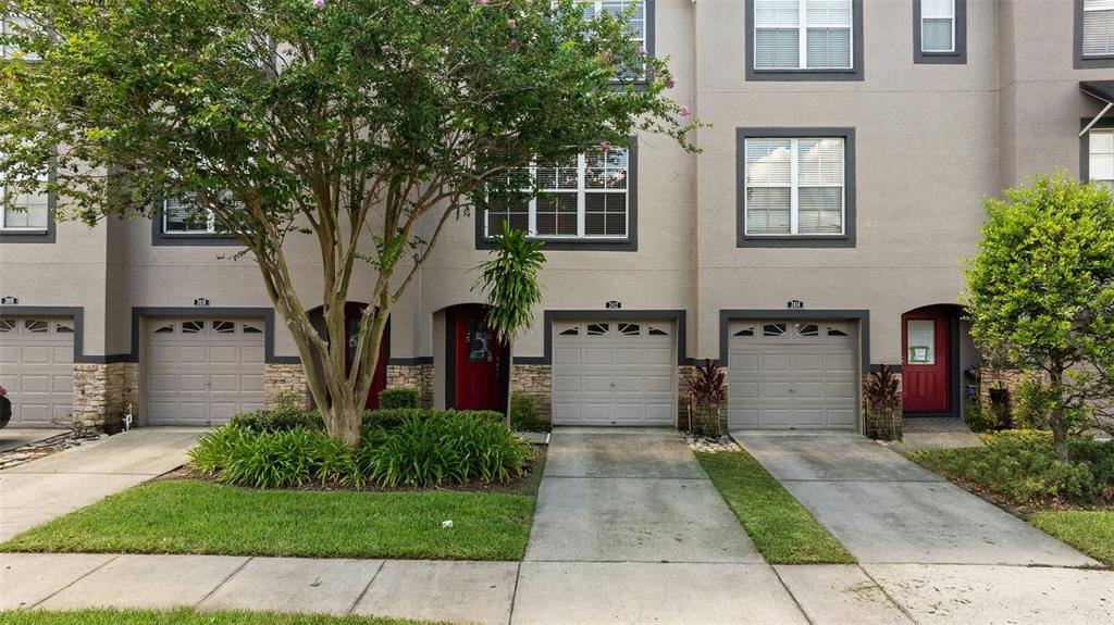 A row of three-story townhomes with beige stucco, stone accents, and attached garages — 2412 MIDDLETON GROVE DRIVE, BRANDON, FL