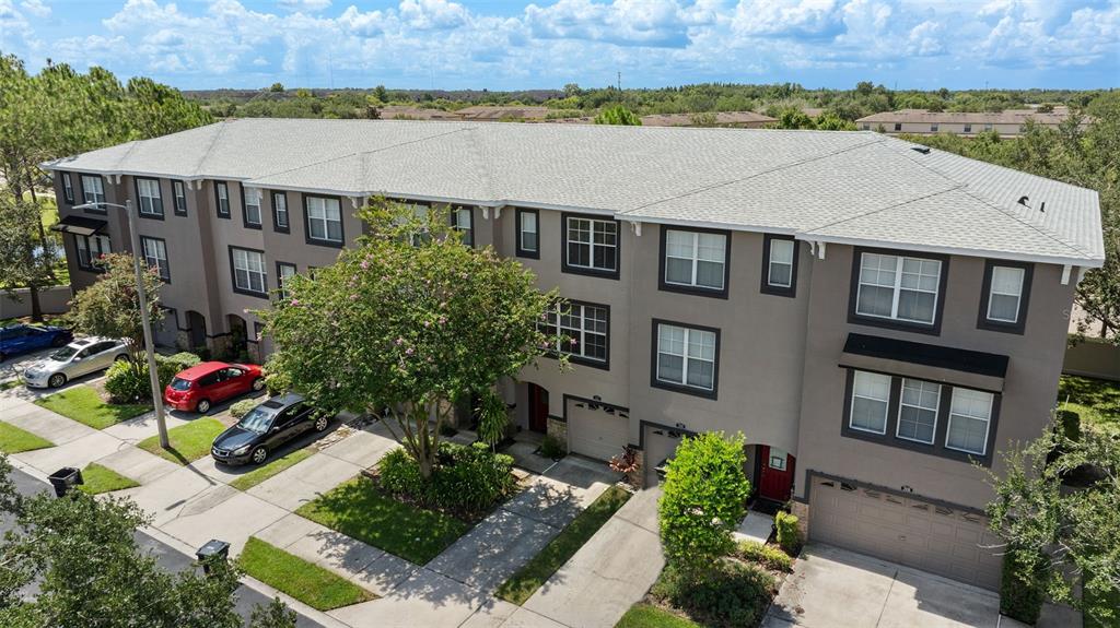 An aerial view of a multi-story brown townhouse complex with attached garages and paved driveways — 2412 MIDDLETON GROVE DRIVE, BRANDON, FL