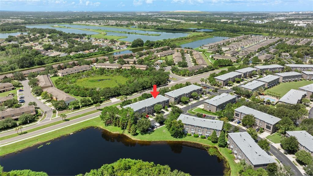 An aerial view shows a multi-story apartment building marked with a red arrow near water — 2412 MIDDLETON GROVE DRIVE, BRANDON, FL