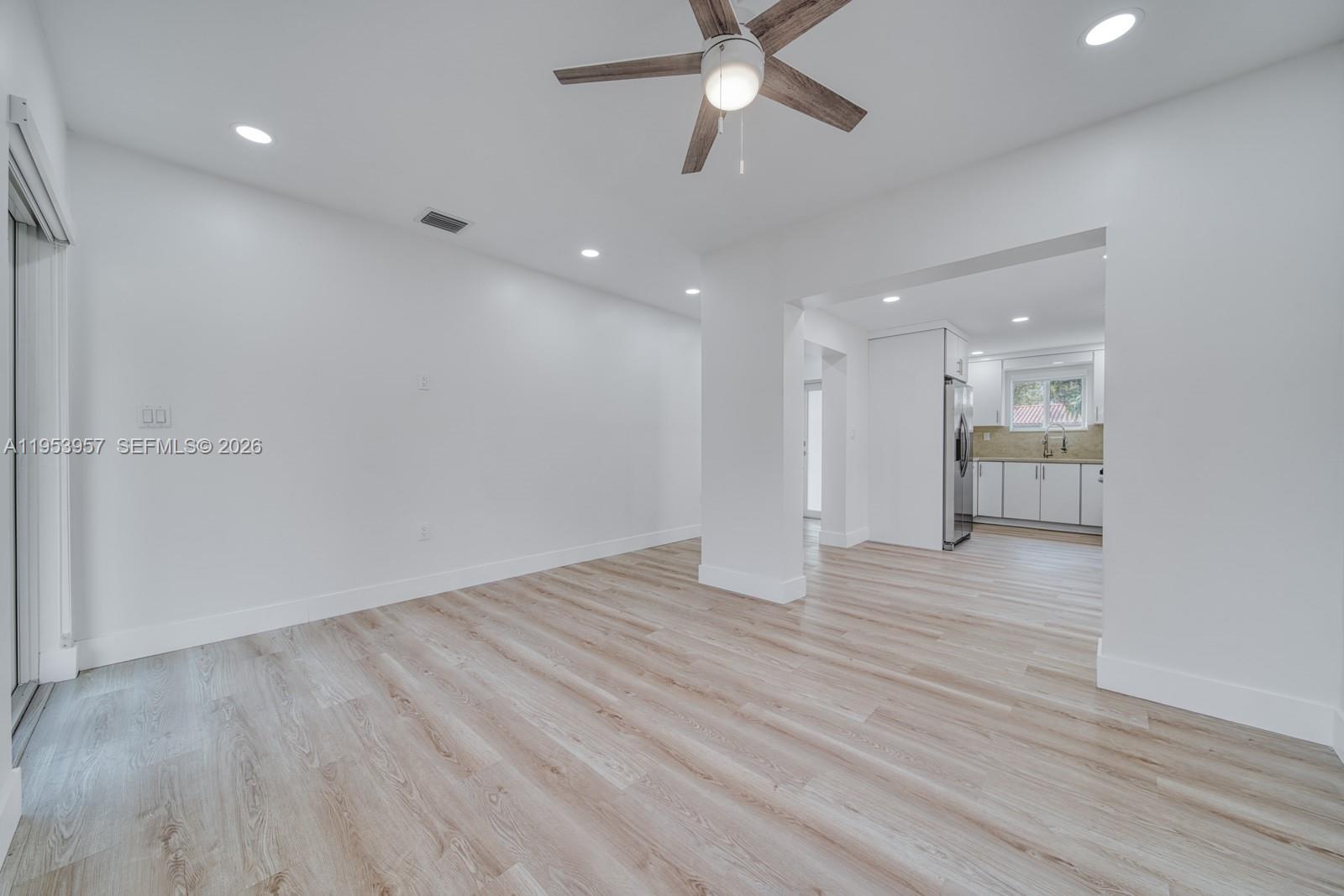 A bright living area with light wood-look flooring opens into a white kitchen — 4345 SW 5th Ter, Miami FL 33134, MIAMI, FL