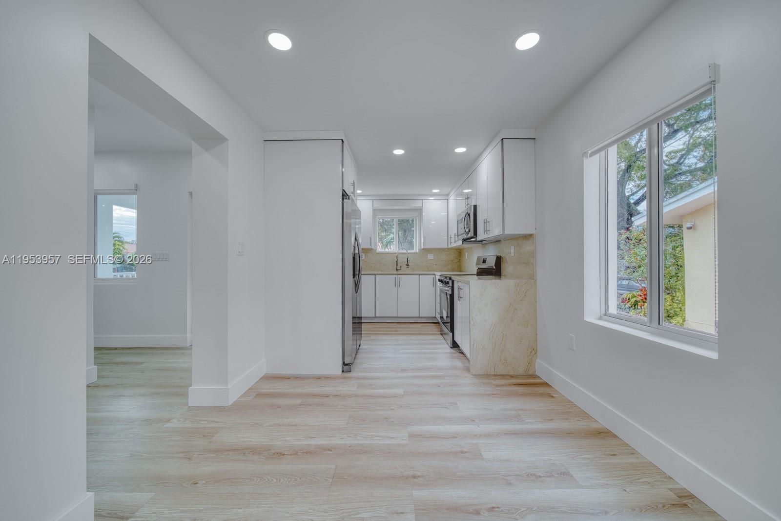 A modern kitchen features white cabinetry, stainless steel appliances, and light wood-look flooring — 4345 SW 5th Ter, Miami FL 33134, MIAMI, FL